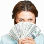 Closeup of woman holding fan of currency notes over white background