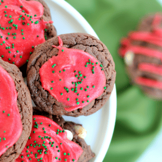 Decadent chocolate cake mix cookies with a mixture of white, dark, and semisweet chocolate chips. Frosted, sprinkled and festive for the holidays.