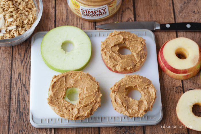 spreading peanut butter over apple slices to make apple sandwiches