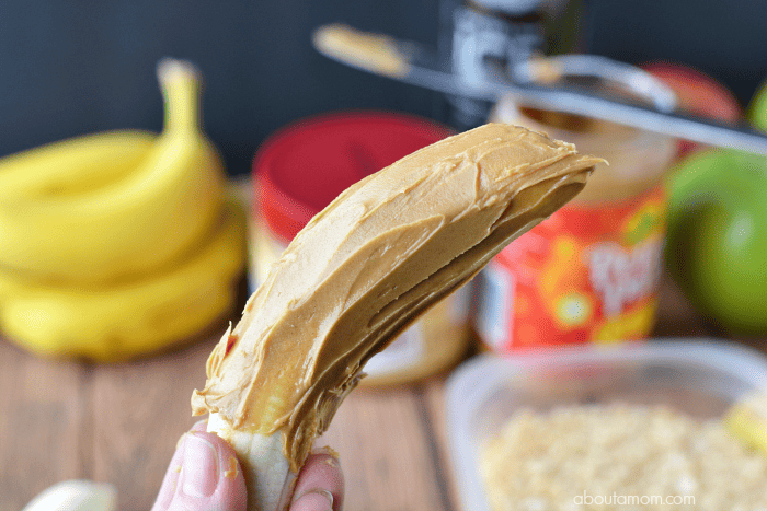 Begin making banana sushi by spreading peanut butter over a banana.