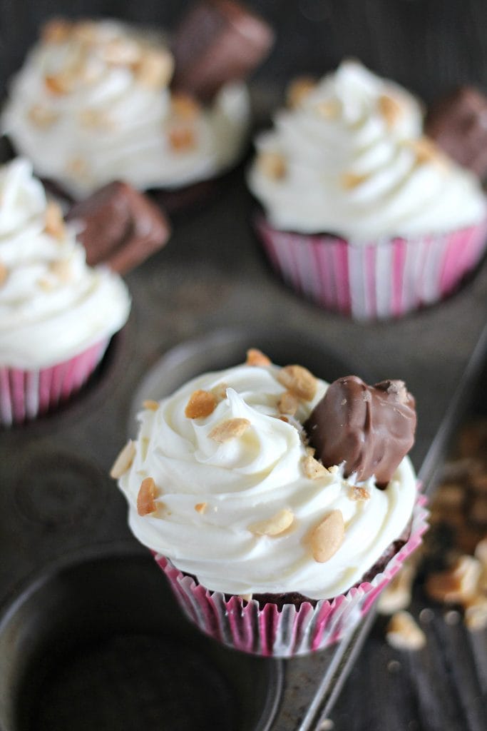 Looking for a cupcake recipe that is sure to be a hit? Love rich caramel, peanuts, and chocolate? You are going to absolutely love these Snicker Cupcakes. Filled with all the goodness of Snickers and topped with the candy themselves, these cupcakes are amazing. Truly, the very best. 