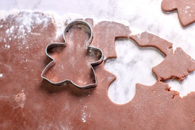 cutting chocolate sugar cookies into gingerbread men