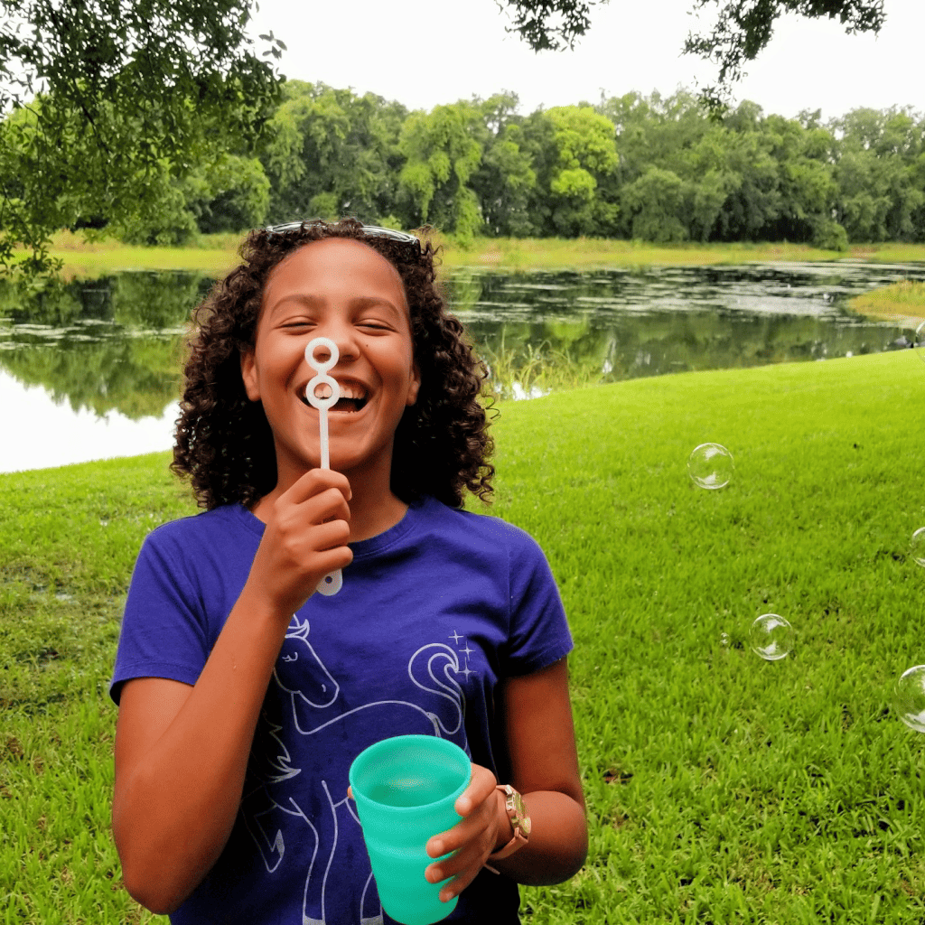 girl having fun blowing bubbles outside