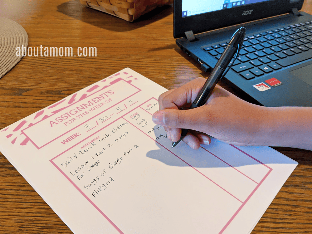 girl filling out assignment sheet for virtual learning