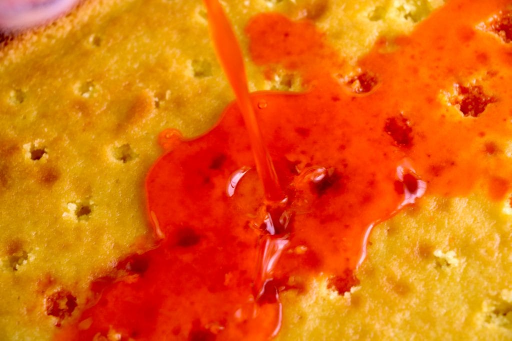 orange glaze being poured over the cake