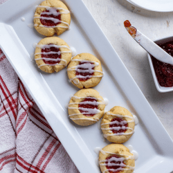 Tender shortbread cookies flavored with almond and filled with raspberry jam are finished of with a sweet almond glaze. Shortbread Thumbprint Cookies are delicious treats that are perfect for holiday baking. These are hands down one of my favorite Christmas cookies to make and make a perfect gift for friends and family.