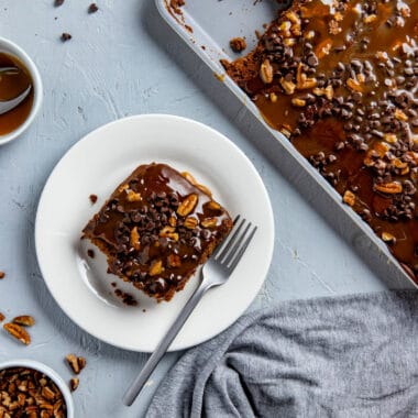 Texas Turtle Sheet Cake recipe is a fun and decadent take on the traditional Texas Sheet Cake. The buttermilk chocolate frosting is topped with chocolate morsels, caramel drizzle and chopped pecans.