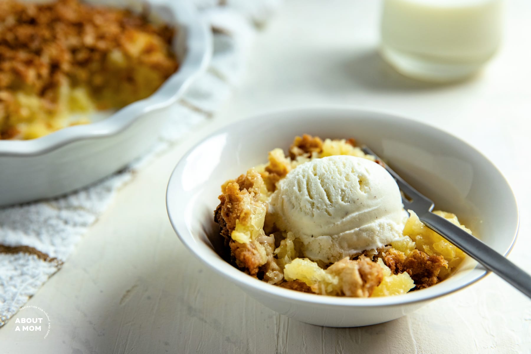 Coconut Pineapple Crisp in a bowl with a scoop of vanilla ice cream